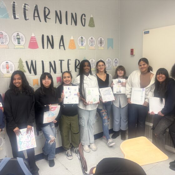 Teen girls pose with artwork they created.