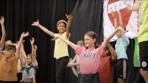 2 young girls smiling with arms outstretched performing during a Circus Minimus Residency in Boonton.