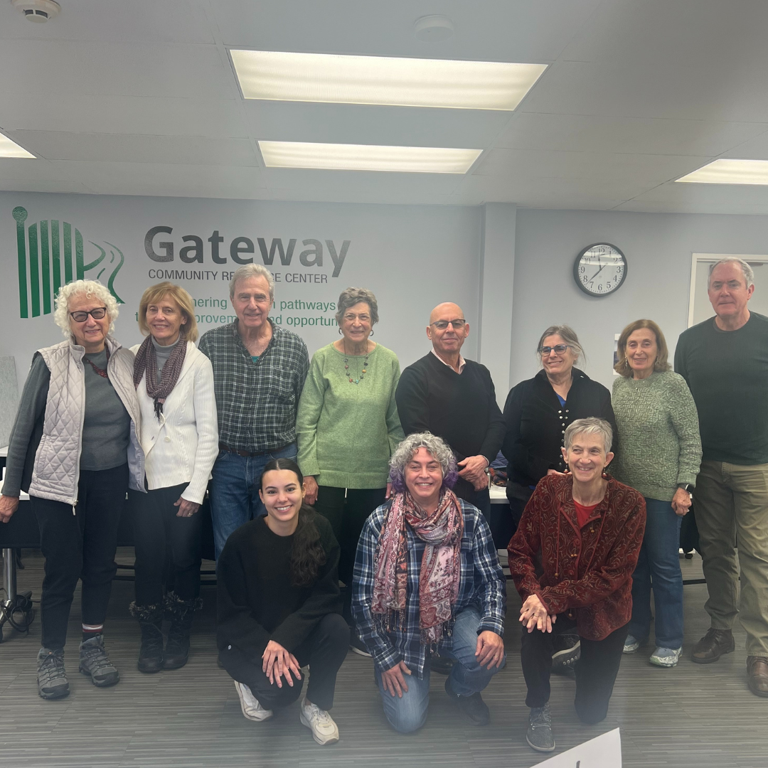 A group of 11 adults poses in front of a wall with a decal saying "Gateway Community Resource Center"